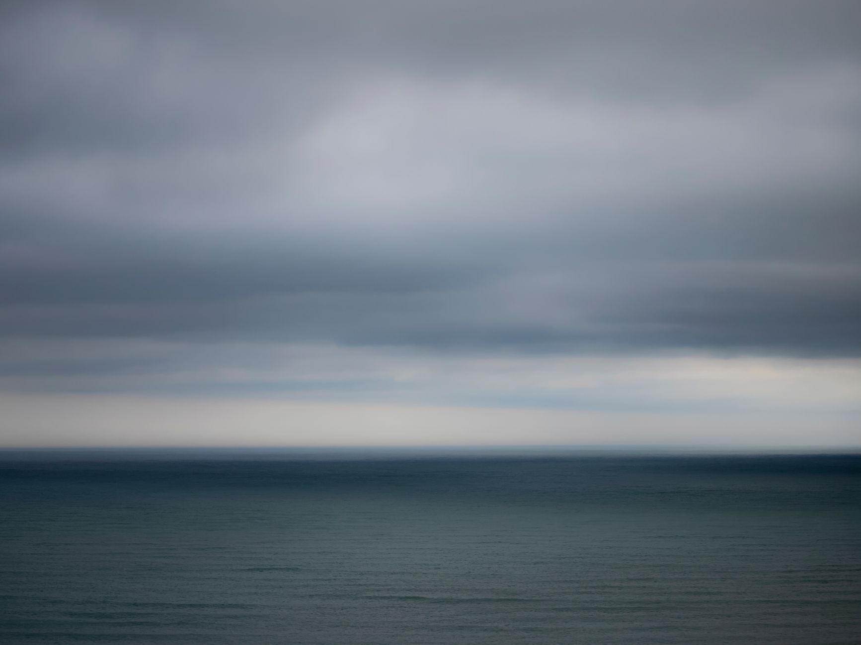 En grå havhorisont under en tung, skyet himmel